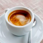 A cup of freshly prepared espresso coffee with foam on fabric, horizontal image